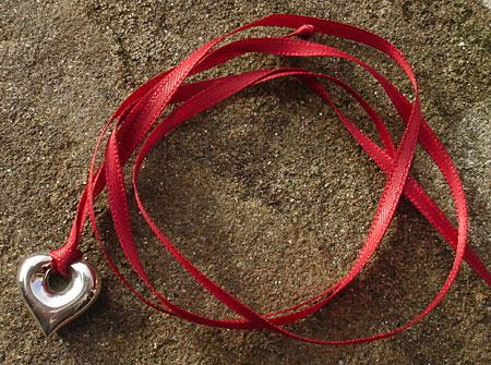 polished silver heart pendant on red ribbon