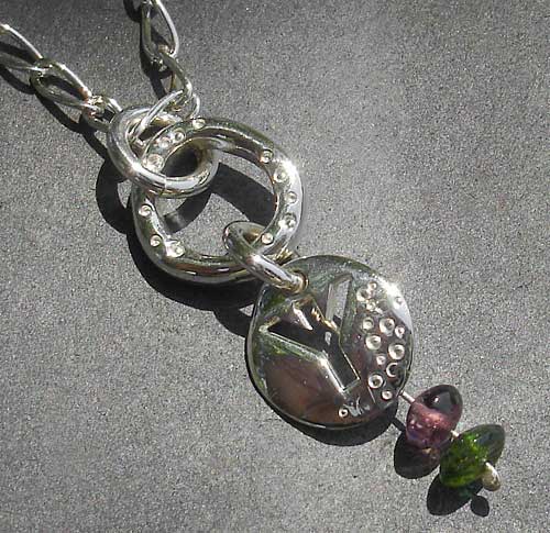 A silver Rune pendant on a silver chain