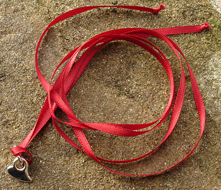 silver heart pendant on red ribbon