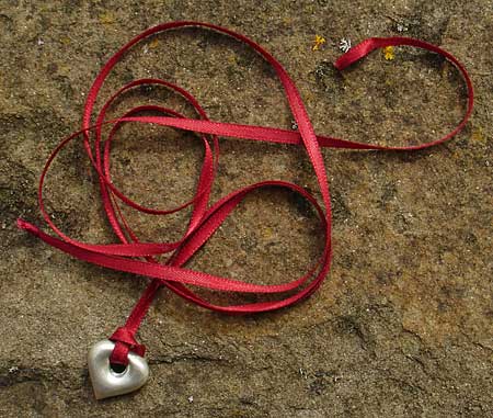 silver heart pendant on red ribbon